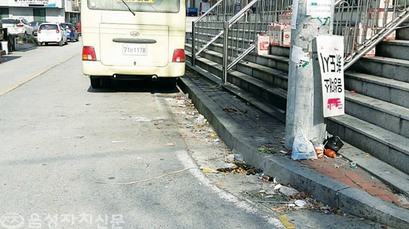 ▲ 금왕읍 주공3차아파트 진입로 주변 도로에 쓰레기가 늘려 있고 광고표지가 거꾸로 매달려 있다.   